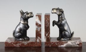 A pair of French patinated metal bookends, each modelled with a Scottie dog, on rouge marble