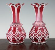 A pair of mid 19th century ruby and white overlaid glass vases, with notched trumpet shaped necks