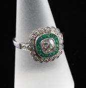 An Art Deco style white gold, emerald and diamond set target cluster dress ring, with diamond set