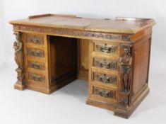 A late Victorian carved oak desk, the top with inset writing surface and hinged central panel,