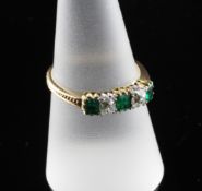 An 18ct gold and five stone emerald and diamond ring, with beaded shoulders, size P.