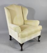 A Georgian style mahogany wing armchair, with striped fabric upholstery and foliate carved legs