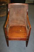 An unusual early 19th century mahogany and brass bound campaign bergere armchair, with caned back