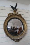 An early 19th century gilt circular convex wall mirror, with carved eagle surmount, H.3ft 5in.