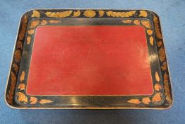 A Regency japanned papier mache oblong tray, with a border of gilt leaves and foliage with red