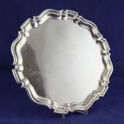 A George V silver salver, of shaped circular form, with pie crust border, on scroll feet, marks