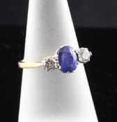An 18ct gold three stone sapphire and diamond ring, with pierced scroll setting, the oval cut