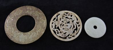 A Chinese pale celadon jade bi disc, 3.1in., together with two serpentine discs, each carved with