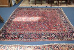 A Heriz rug, with field of geometric foliate motifs, on a red ground, with three row border, 7ft