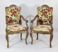 A set of four Louis XV style carved walnut open armchairs, the upholstered backs and seats with