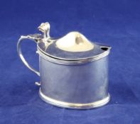 An Edwardian silver oval mustard pot, with reeded rim and scroll thumbpiece, Crichton Brothers,