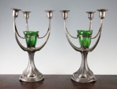 A pair of Continental Art Nouveau silvered pewter three branch candelabra, with green glass