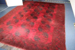 An Afghan carpet, with field of twenty one octagons, on a deep red ground, with multi row border,