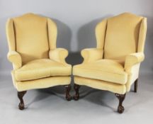 A pair of Georgian style wing armchairs, with yellow fabric upholstery and claw and ball feet