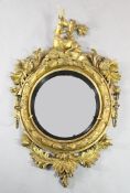 A Regency giltwood convex girandole wall mirror, with seated stag crest, scrolling flowers and