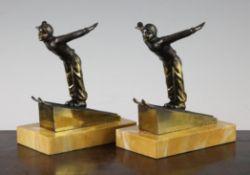 A pair of Art Deco bronze bookends, modelled as ski jumpers, on rectangular yellow marble bases,