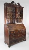 A George III mahogany bureau bookcase, with broken swan neck pediment, arched glazed doors over a