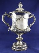 An ornate Victorian silver presentation two handled pedestal trophy cup and cover, embossed with