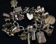 A late 1960`s 9ct gold chain link charm bracelet, with heart shaped padlock and hung with thirty one