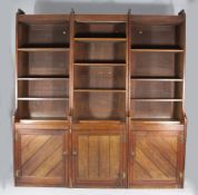 A large Arts & Crafts walnut library bookcase, with open shelves over three panelled doors, one door