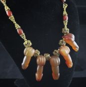 A gilt metal cage link and agate bead necklace hung with five graduated carved agate phalli, 15in.