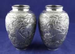 A pair of late 19th/early 20th century Persian silver vases, of ovoid form, embossed with continuous