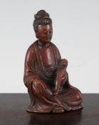 A Chinese soapstone seated figure of Guanyin, holding a ruyi sceptre in her left hand, the red