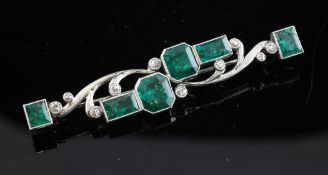 A 1920`s gold, silver emerald and diamond bar brooch, of scrolling and geometric design set with