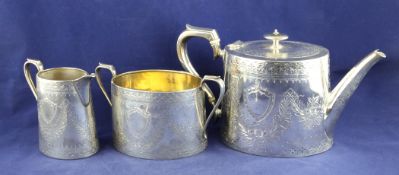 A Victorian silver three piece tea set, of oval form, with engraved foliate swag decoration,