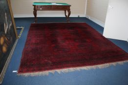 An Afghan carpet, with two rows of five octagons, on a deep red ground, with multi row geometric