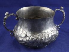 An early Charles II silver porringer, of circular bellied form, with caryatid handles and embossed