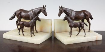 A pair of 20th century patinated bronze and onyx bookends, each modelled with a horse and foal,