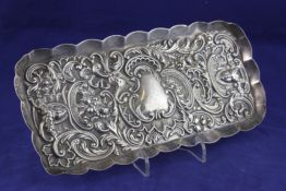 An Edwardian silver pin tray, by William Comyns, of rectangular form, with shaped rim and embossed