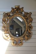 A rococo revival giltwood oval wall mirror, the border profusely carved and pierced with acanthus