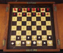 A 19th century mahogany folding travelling chess set, with red stained and natural bone opposing