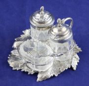 A Victorian silver leaf shaped cruet stand, with ring handle, two silver mounted bottles and a plain