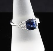 An 18ct white gold sapphire and diamond set dress ring, the cushion cut sapphire weighing