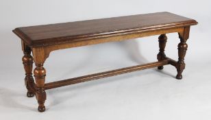 A late Victorian Howard & Sons oak window seat, with turned cup and cover supports and `H` frame