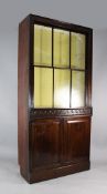 A 19th century mahogany bookcase, with unusual sliding sash glazed panels over a pair of cupboard