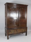 An 18th century oak cupboard, fitted a pair of panelled doors over single drawer, on square