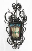 A Victorian style wrought iron hall lantern, with four stained glass panels and scrolling leaf
