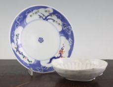 Two Japanese Kakiemon dishes, the first oval, painted to the centre with a prunus branch, scallop