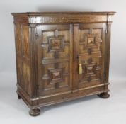An 18th century oak inlaid two door cupboard, with geometric moulded door panels and bun feet, W.4ft