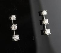 A pair of 18ct white gold and triple diamond set earrings, total diamond weight approximately 1.