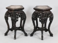 A pair of Chinese pentagonal shaped urn stands, with circular marble inset tops, carved and