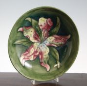 A Walter Moorcroft `Lily` shallow bowl, on dark to pale green ground, inscribed `W.M` mark,