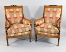 A set of four French Empire style beech fauteuils, with rosette and husk decorated crest rails