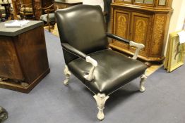 A large pair of black leather open armchairs, with white painted stiff leaf and eagle head carved