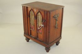 An early 19th century mahogany barrel organ or serinette, with a gothic arched front and four turned