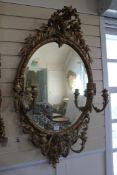 A Victorian carved oval giltwood girandole wall mirror, with bird and leaf crest and six scrolling